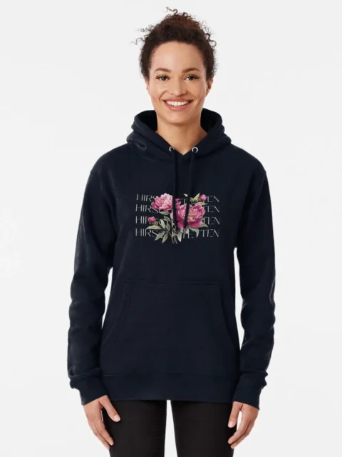 Smiling woman wearing a black hoodie with a floral design and 'Hirschtetten Vienna' text, representing casual fashion inspired by Hirschtetten, Vienna.