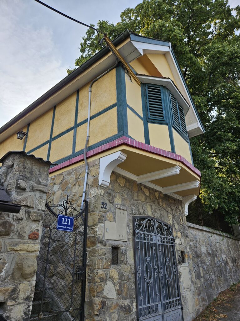 A charming, historic house with half-timbered design and stone walls in Stammersdorf, featuring a decorative iron gate and vibrant architectural details.