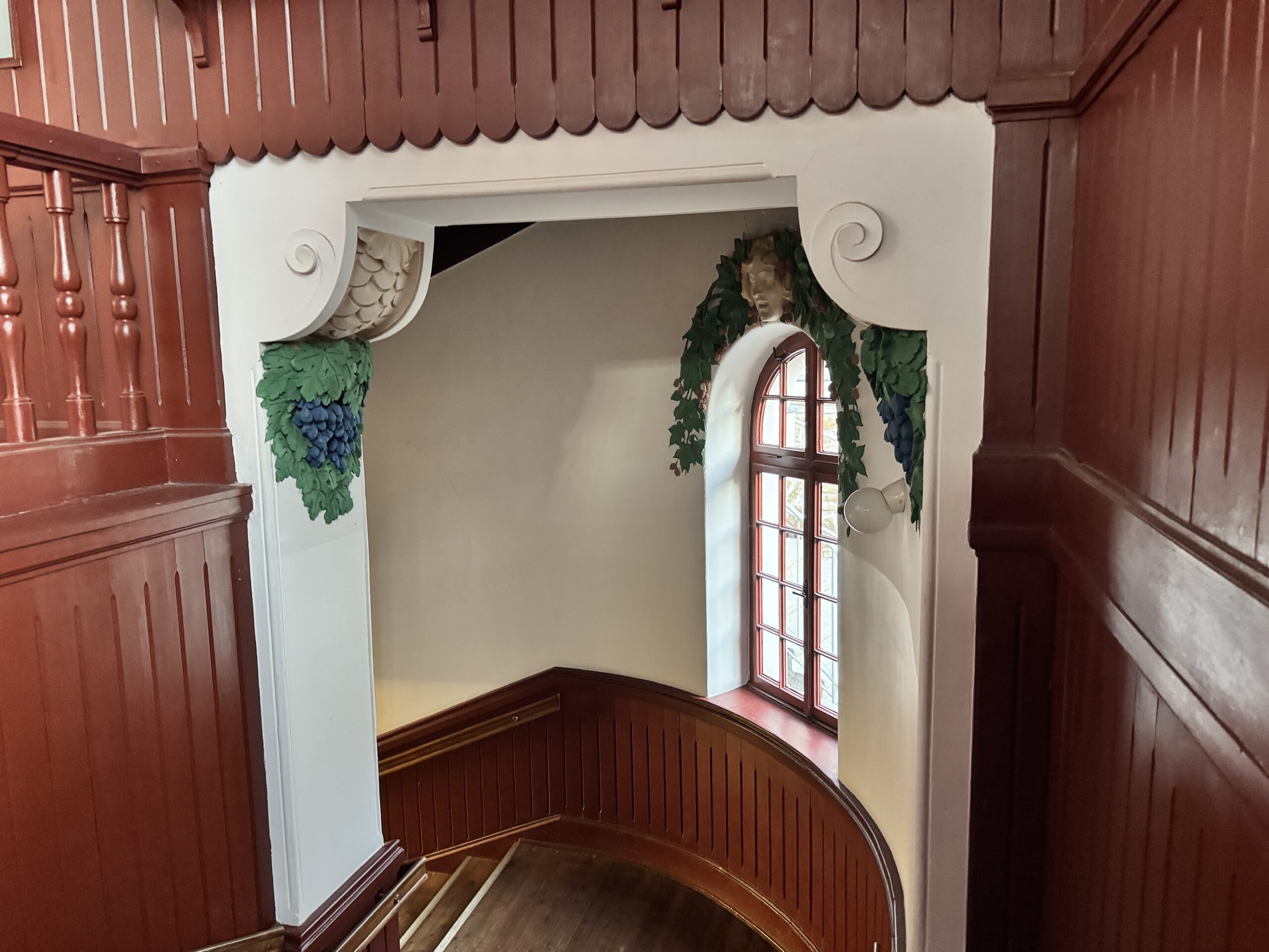 Interior decorations inside the Krapfenwaldbad building, featuring intricate carvings and grape motifs that reflect the local history and might have been admired by former restaurant guests.