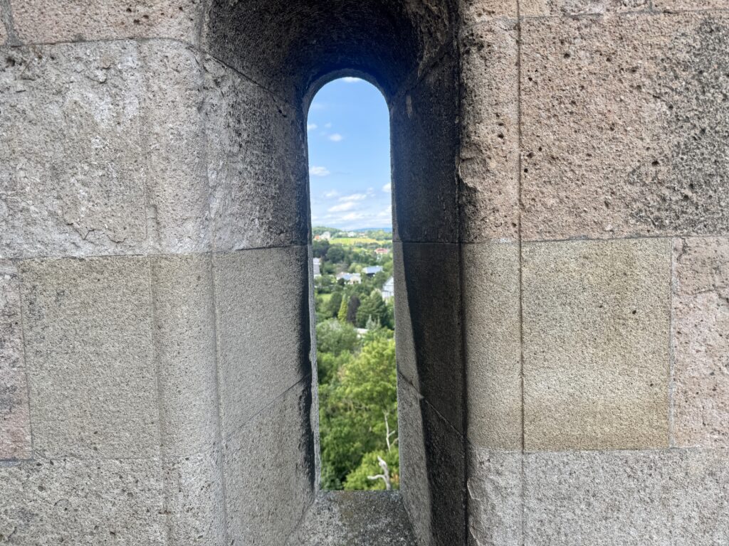 A view of the landscape seen through a narrow window in Burg Lichtenstein, overlooking the greenery and village below.