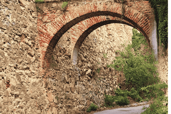 Brick archway on Eichelhofstraße, Vienna, with stone walls and greenery.