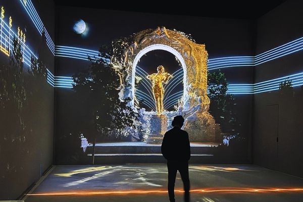 Visitor viewing the illuminated Johann Strauss monument display at the "New Dimensions" exhibition in Vienna.