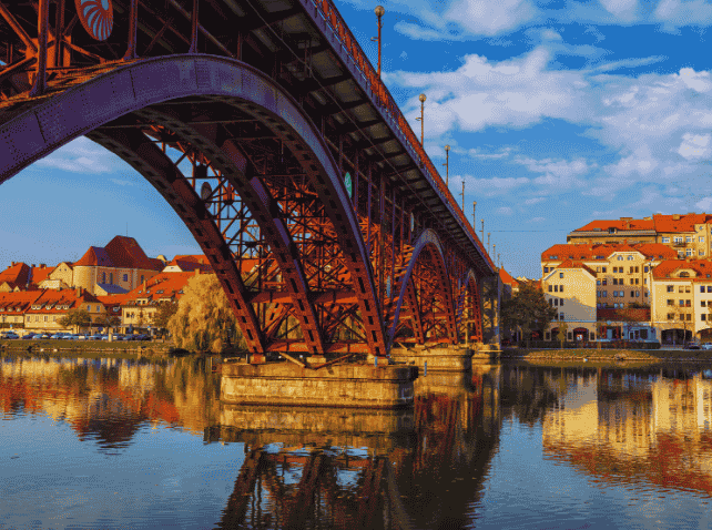 Maribor's historic bridge over the Drava River with reflections.