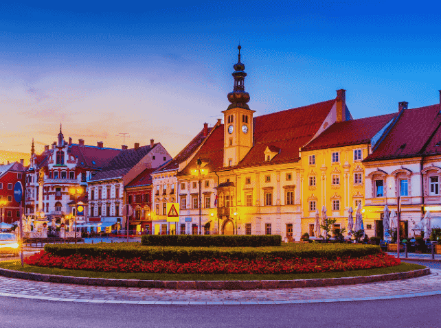 Maribor city center at sunset with historic buildings and clock tower.