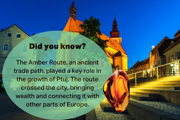 Night view of Ptuj, Slovenia, showing a historic church and a glowing amber sculpture representing the Amber Route’s influence on the city’s development.