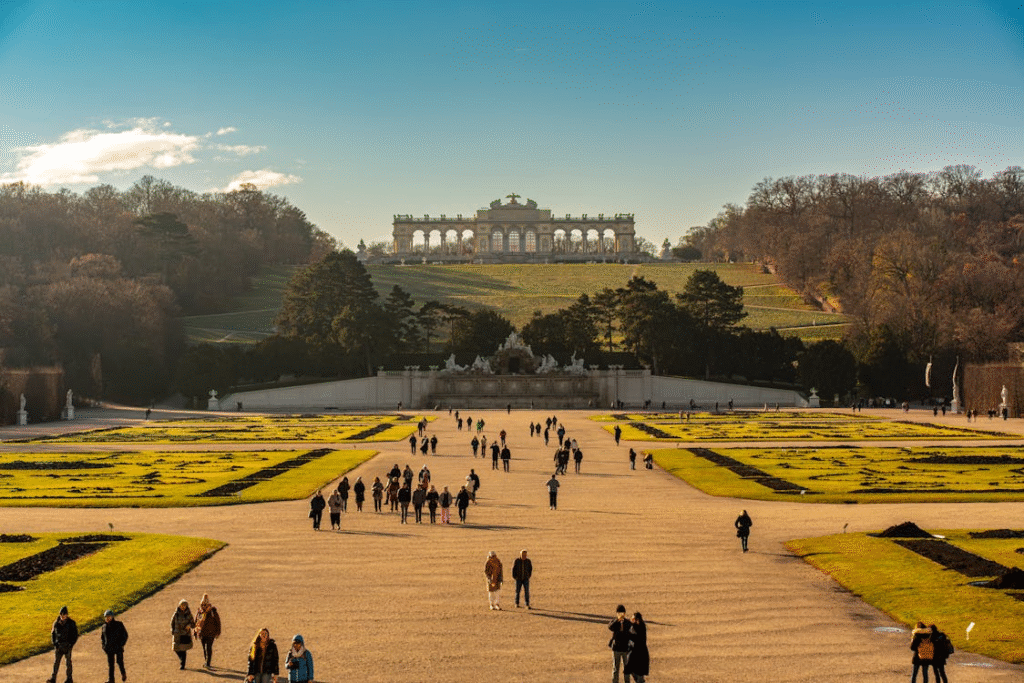 Gardens of Schönbrunn Palace with people walking toward the Gloriette in Vienna
