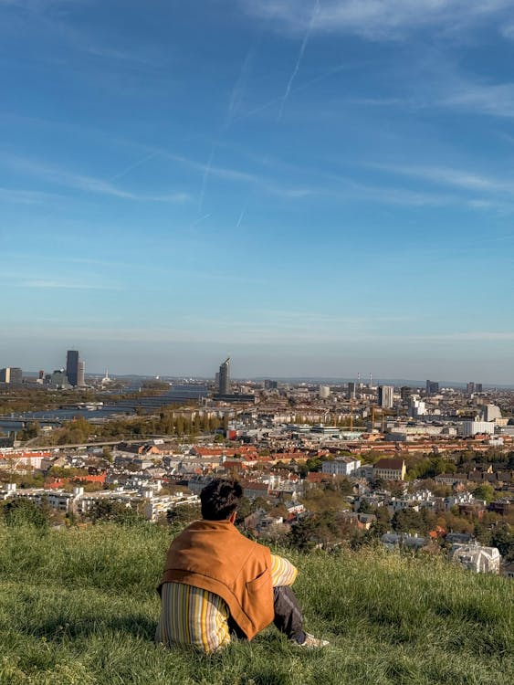 Person sitting on Kahlenberg hill with panoramic view of Vienna and the Danube